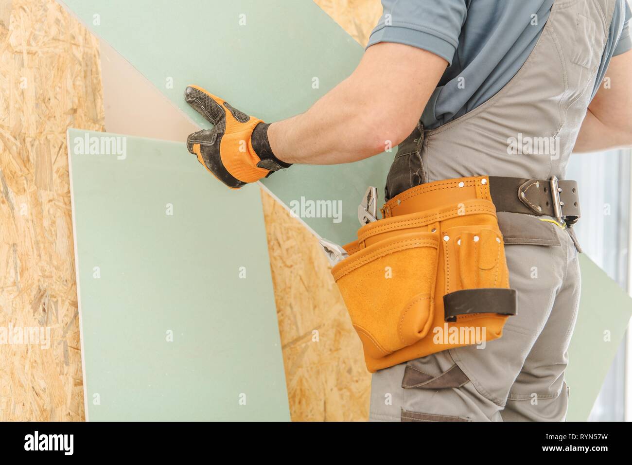 Rimodellamento casa lavoratore. Uomini caucasici con un pezzo di muro a vista in mani. La costruzione di nuove mura. Industria di costruzione del tema. Foto Stock