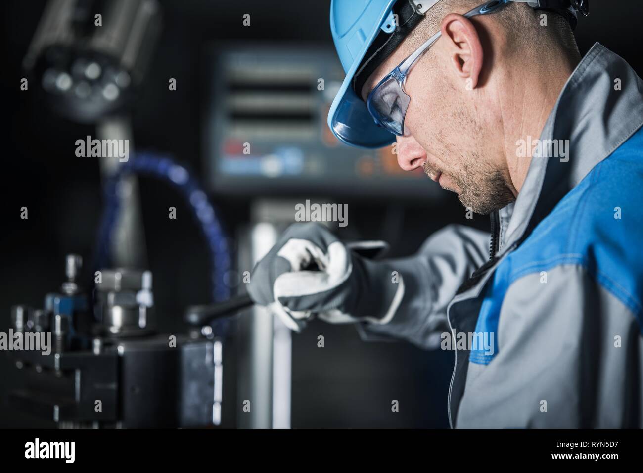 Lavorazione dei metalli tecnico al lavoro. Caucasica operaio di fabbrica in blu di elmetto e occhiali di sicurezza. Foto Stock