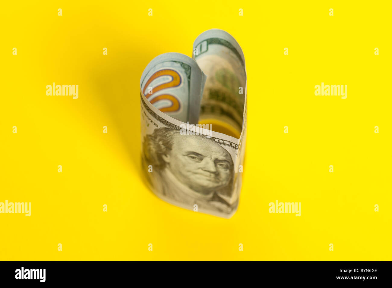 Cuore di 100 US dollar nota su sfondo giallo Foto Stock
