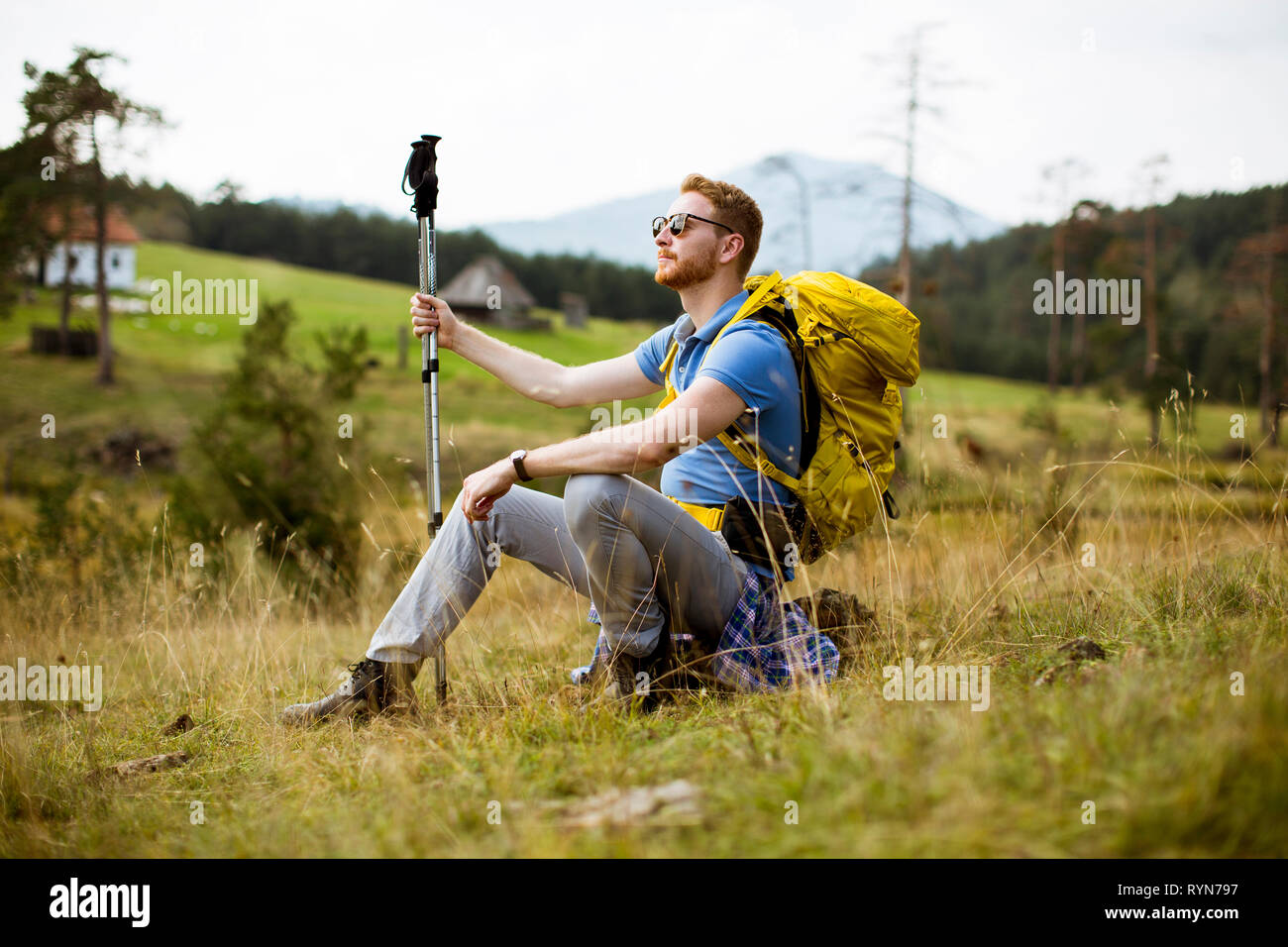 Bel giovane capelli rossi backpacking uomo resto presso la collina Foto Stock