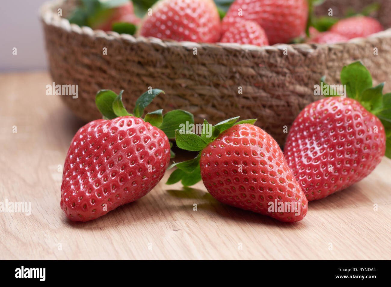 Close up di fragole fresche con legno naturale sfondo in un cestello Foto Stock