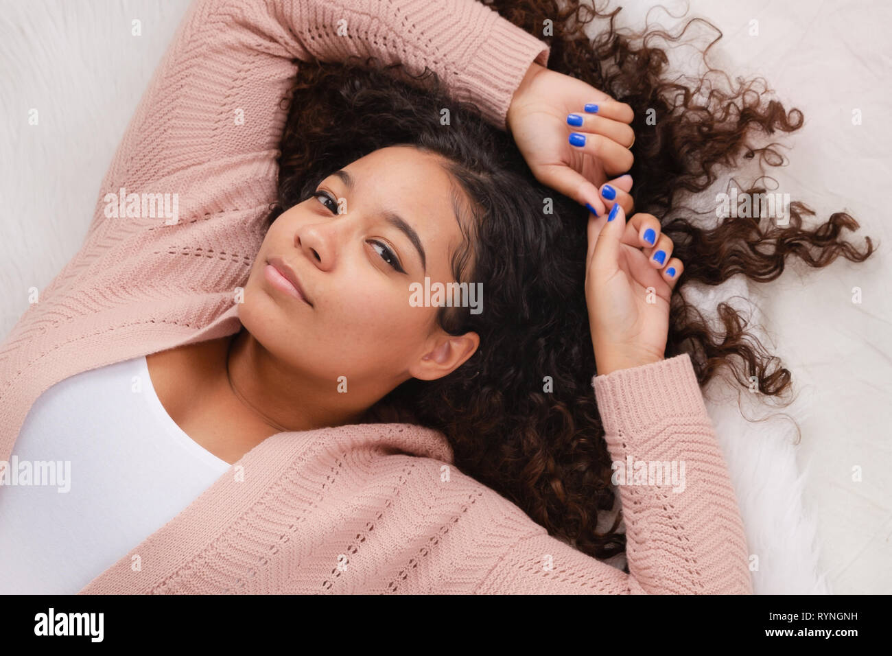 Attraente biracial high school senior che stabilisce su pavimento in posa per ritratti Foto Stock