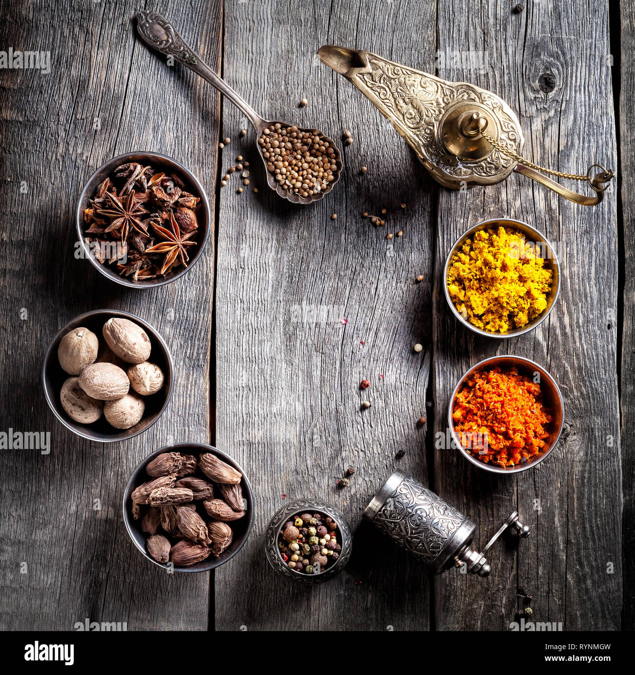 Spezie, pepe macinino, lampada Aladdin, cucchiaio con semi in grigio sullo sfondo di legno Foto Stock