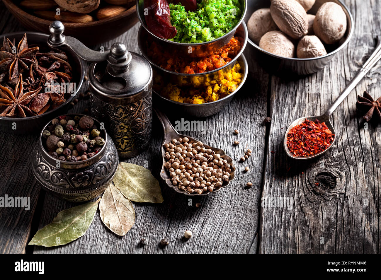 Spezie, pepe macinino, cucchiaio con semi vicino fino al grigio Sfondo di legno Foto Stock