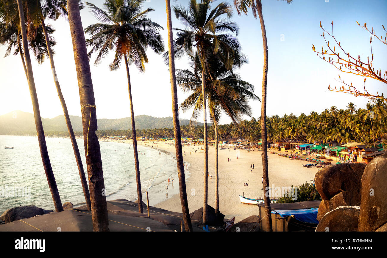 Bella vista panoramica del tramonto tropicale spiaggia con bungalow e palme di cocco a Palolem in Goa, India Foto Stock