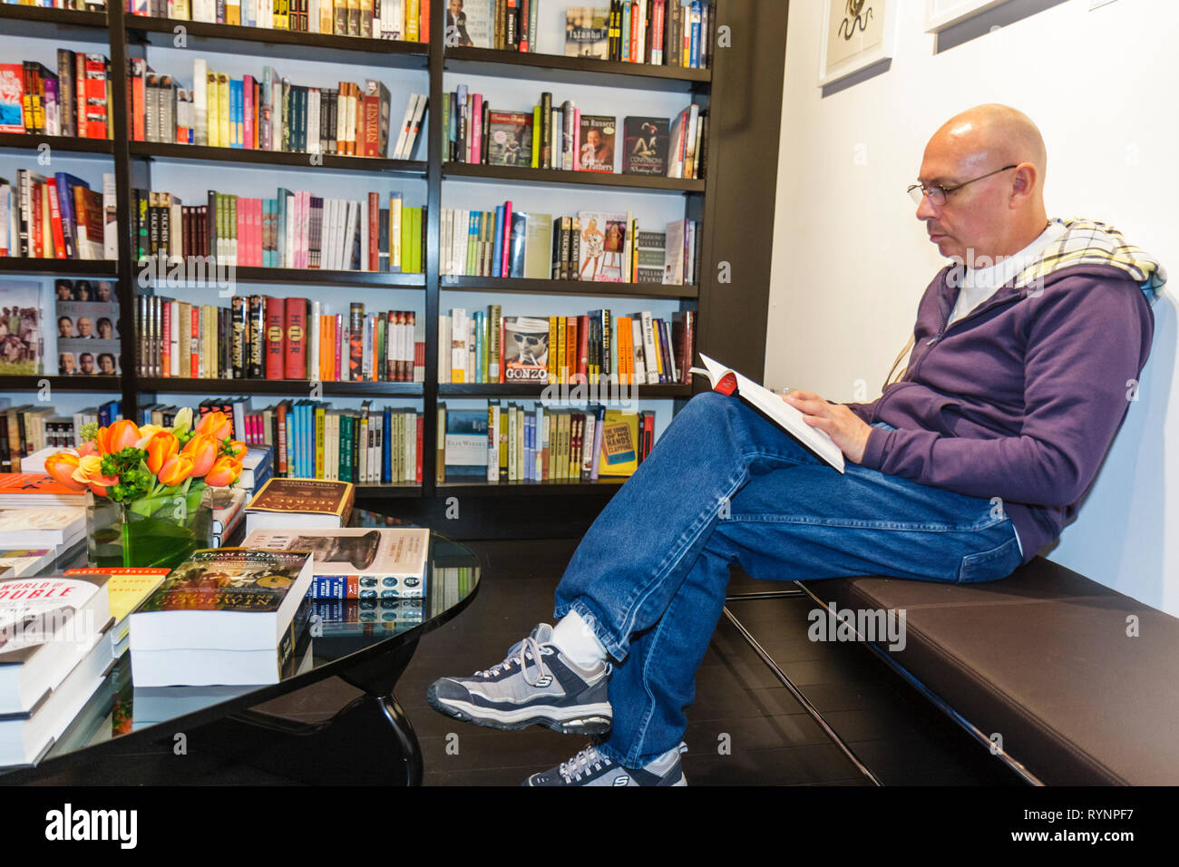 Miami Beach Florida, Lincoln Road Mall, libri e libri, libreria, libreria, riapertura uomo uomini maschio, calvo, seduta, libreria, lettura, tavolino, panca, ambiente Foto Stock
