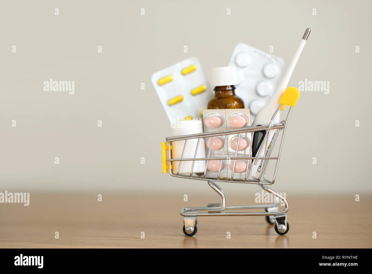 Carrello spesa giocattolo con medicamenti: pillole, blister, bottiglie di medici, termometro set. La cura della salute e la medicina del concetto. Copia gratuita dello spazio. Foto Stock