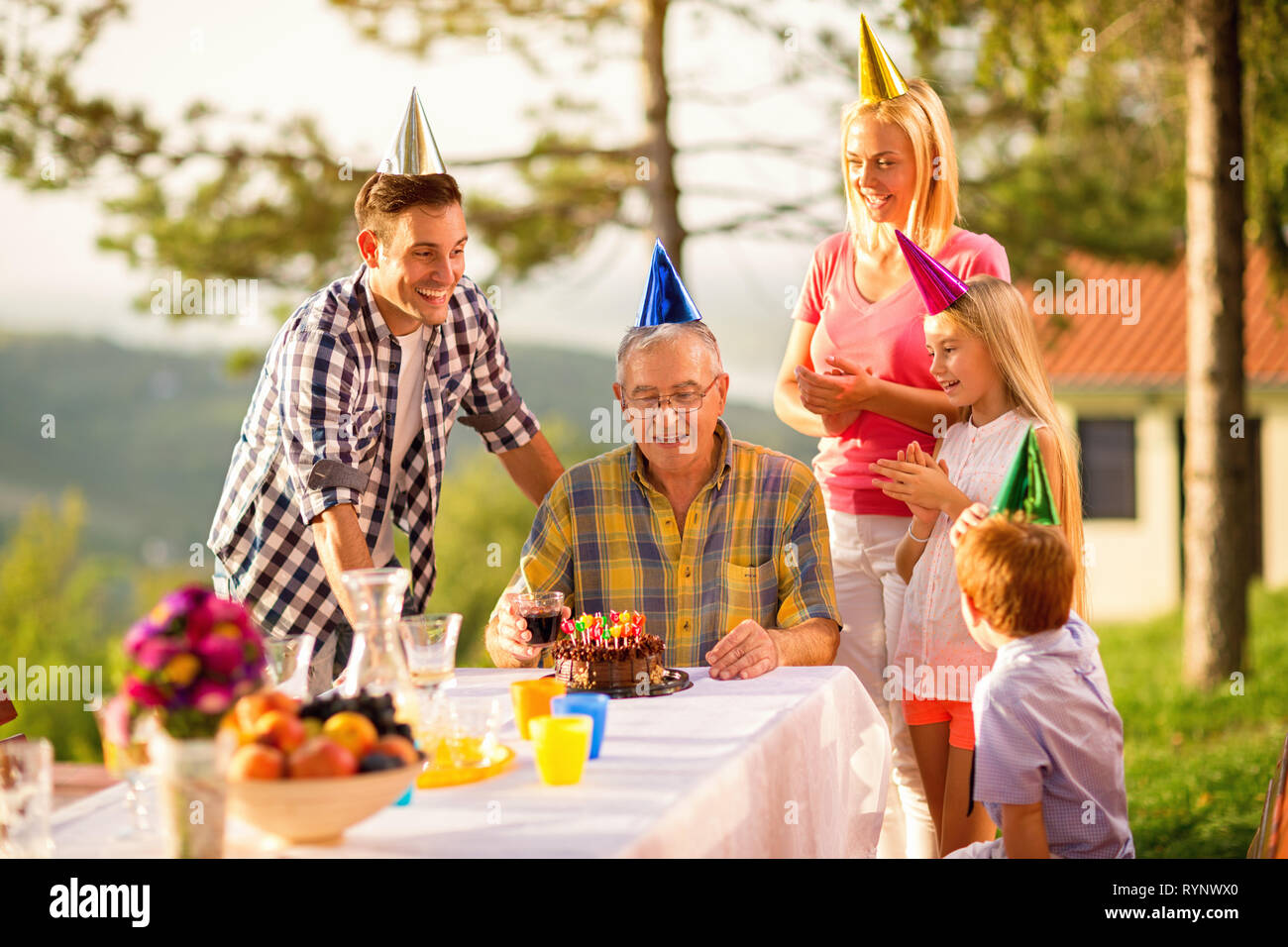 Famiglia festeggia il compleanno di nonno insieme in giardino Foto Stock