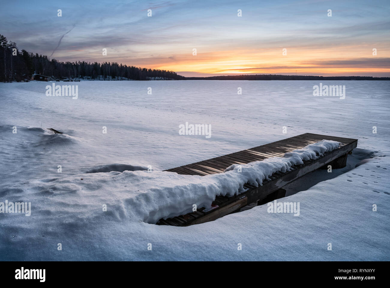 Scenic paesaggio invernale con Pier e il tramonto a luce della sera in Finlandia Foto Stock