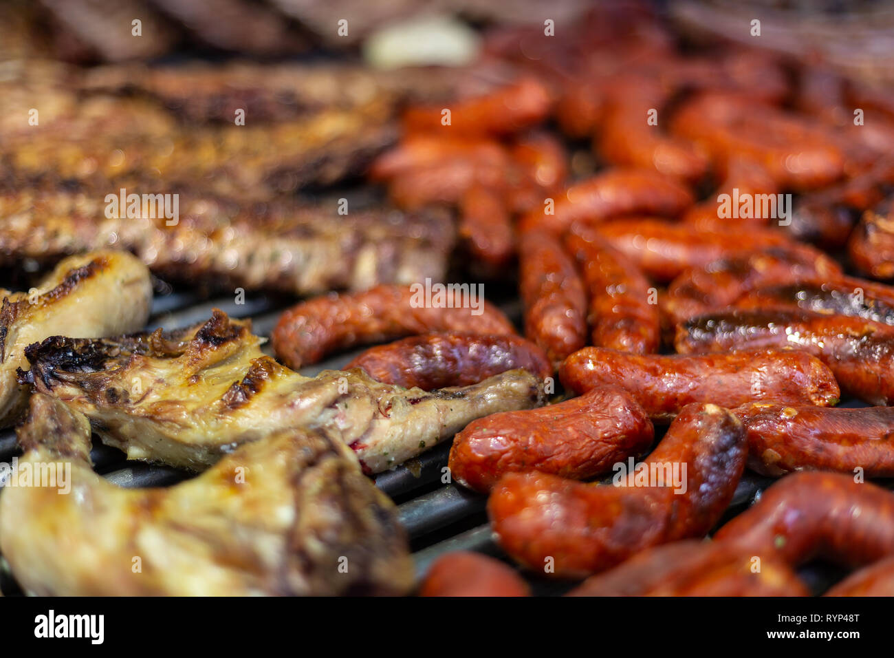 Costolette di maiale e salsicce alla griglia in un barbecue Foto Stock