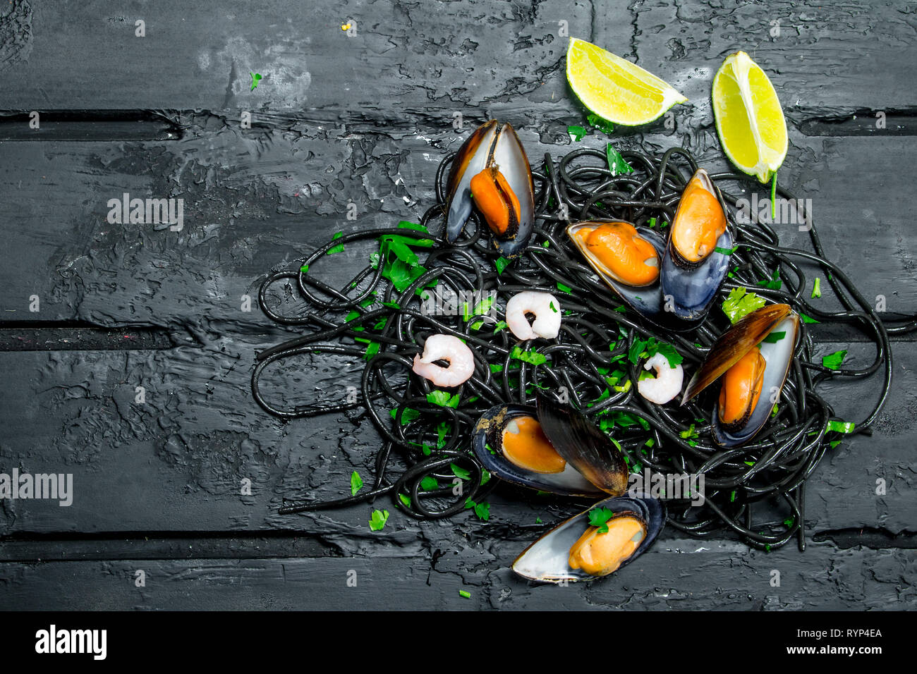 Cucina mediterranea. Spaghetti al nero di seppia e vongole. Nero su sfondo rustico. Foto Stock