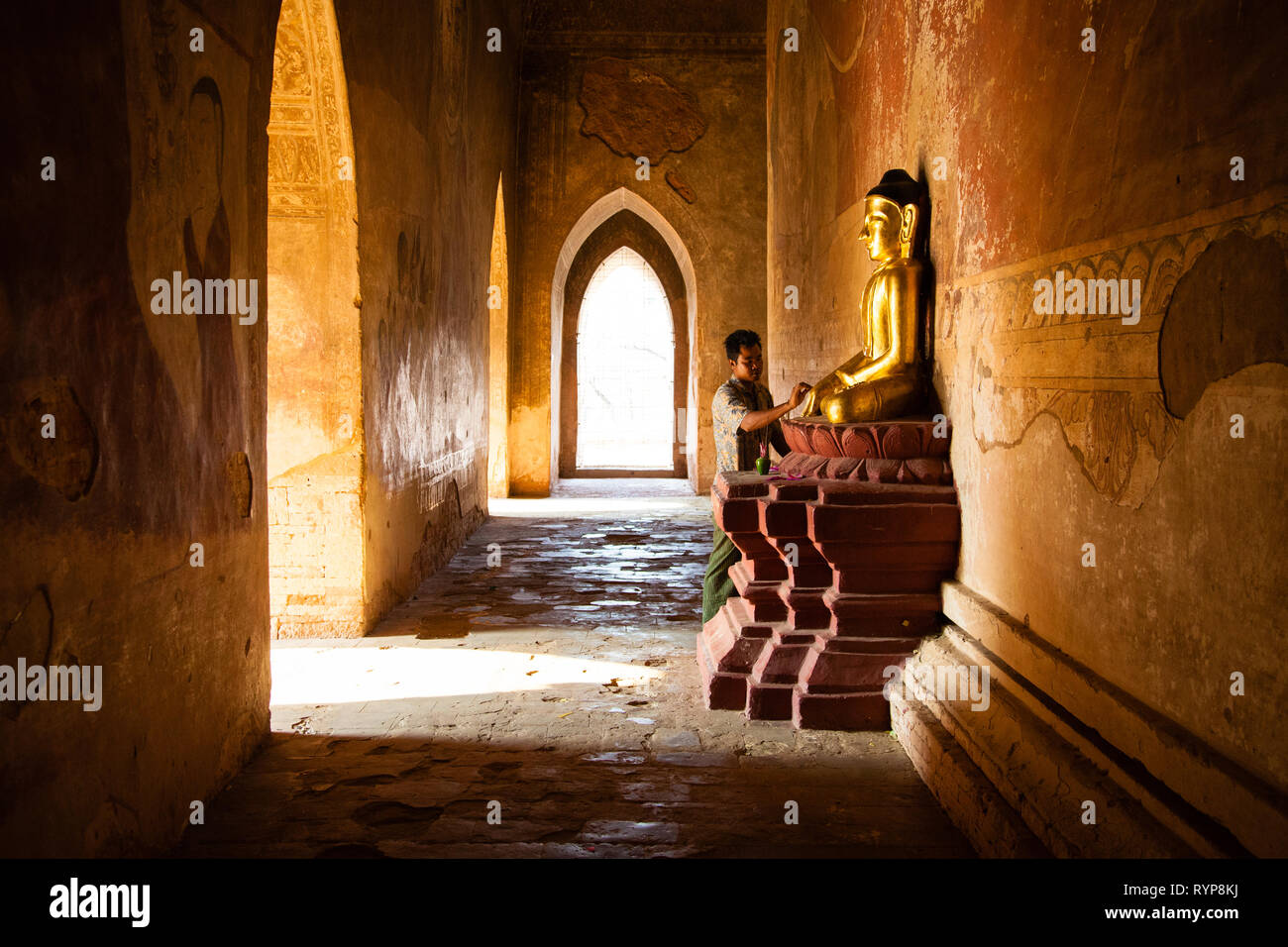 Un uomo dice una preghiera per un Buddha d'oro all'interno Sulamani Pahto tempio di Bagan Foto Stock