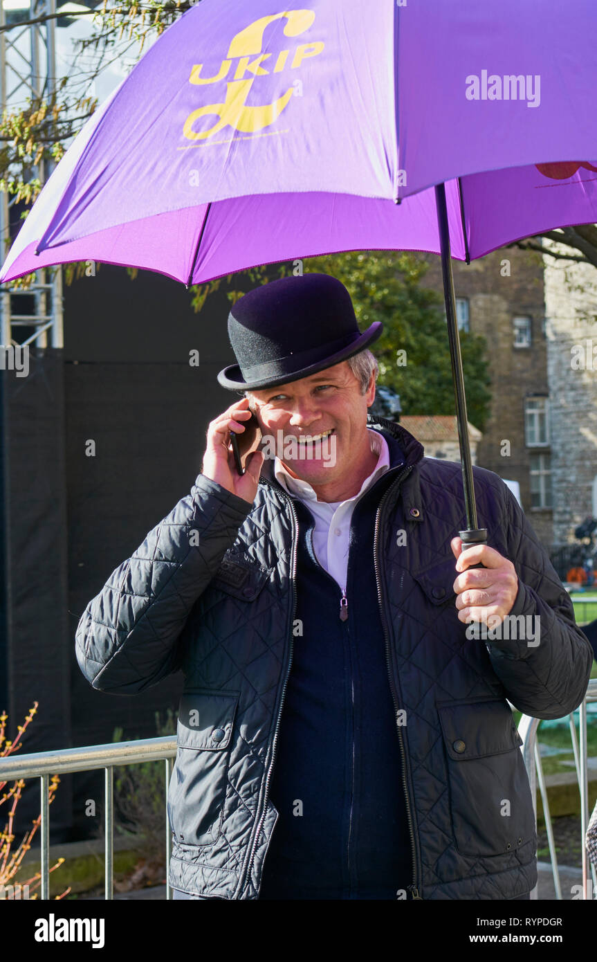 Westminster, Londra, Regno Unito. 14 mar 2019. Il UKIP sostenitore con ombrellone a parlare sul suo 'telefono, al di fuori del Palazzo di Westminster, il giorno di un voto determinante su un possibile ritardo per Brexit, il 14 marzo 2019 Credit: Richard Barnes/Alamy Live News Foto Stock