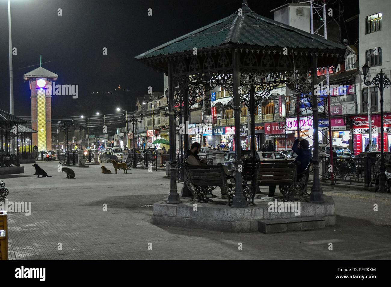 I visitatori si vede in riposo sotto un riparo accanto alla torre dell orologio a un hub commerciale Lal chowk durante la serata a Srinagar Kashmir. Il Kashmir è il più settentrionale della regione geografica del subcontinente indiano. Attualmente è della contestazione di un territorio amministrato da tre paesi: India, Pakistan e Cina. Foto Stock