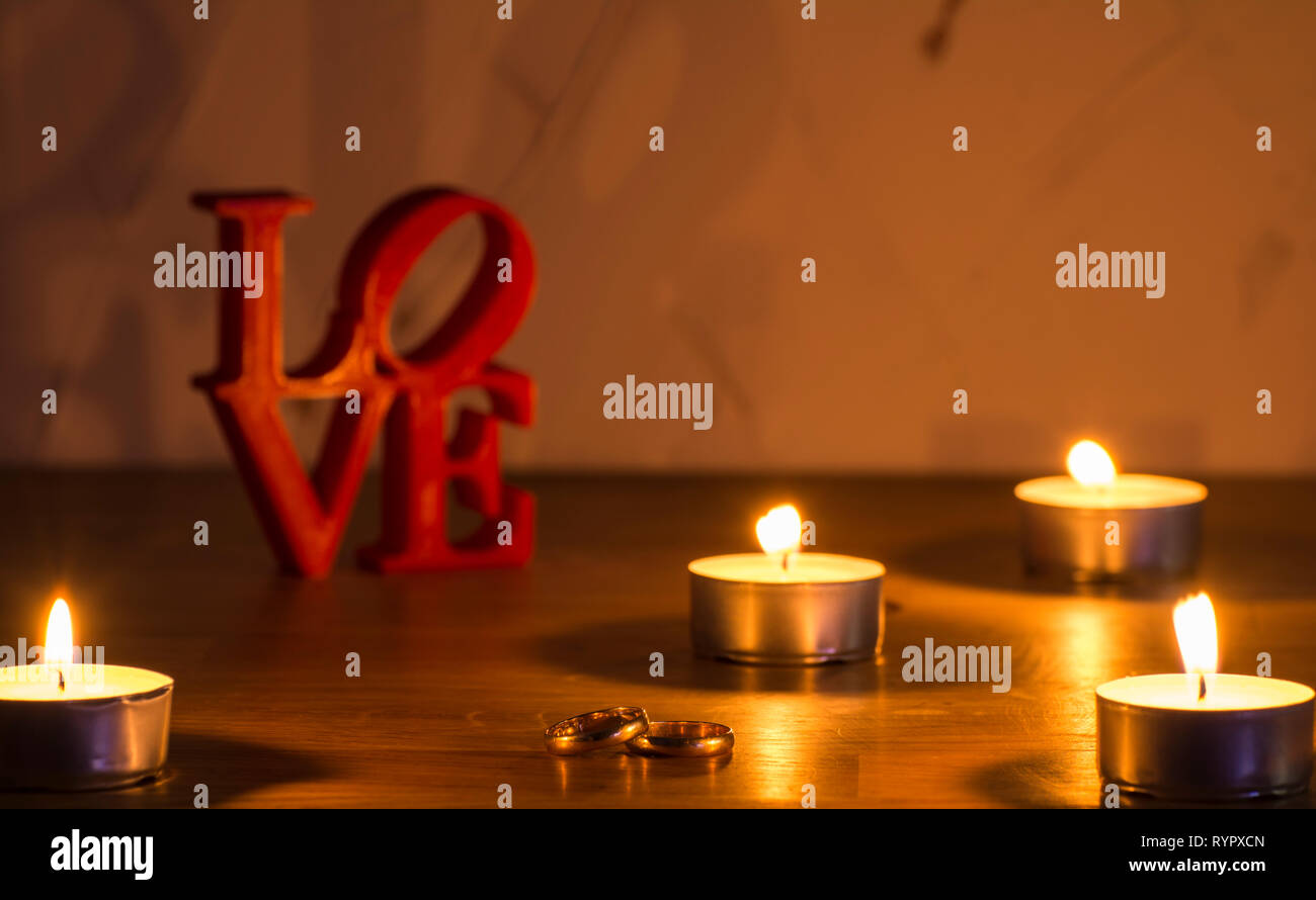 Red lettere di amore su sfondo bianco sulla sinistra con due anelli e candele Foto Stock