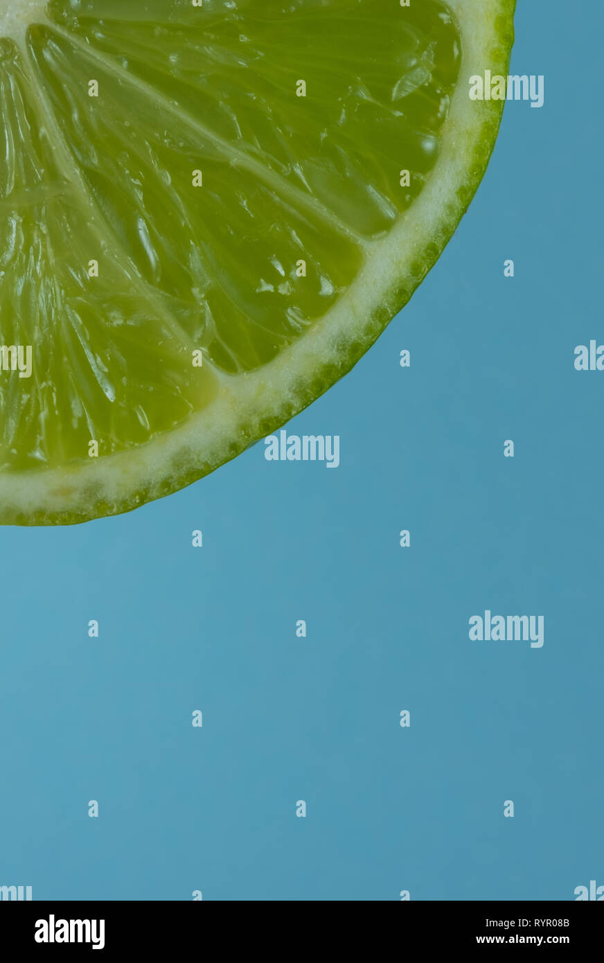 Immagine macro di un trimestre di lime fetta su uno sfondo blu Foto Stock