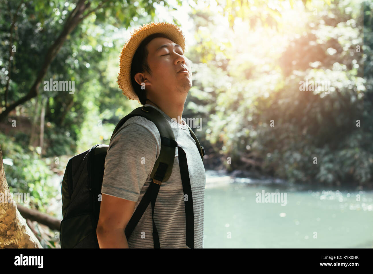 Giovane maschio asiatici traveler godendo ed inspirando aria salubre in natura verde foresta - aria fresca e la vita di benessere. Foto Stock