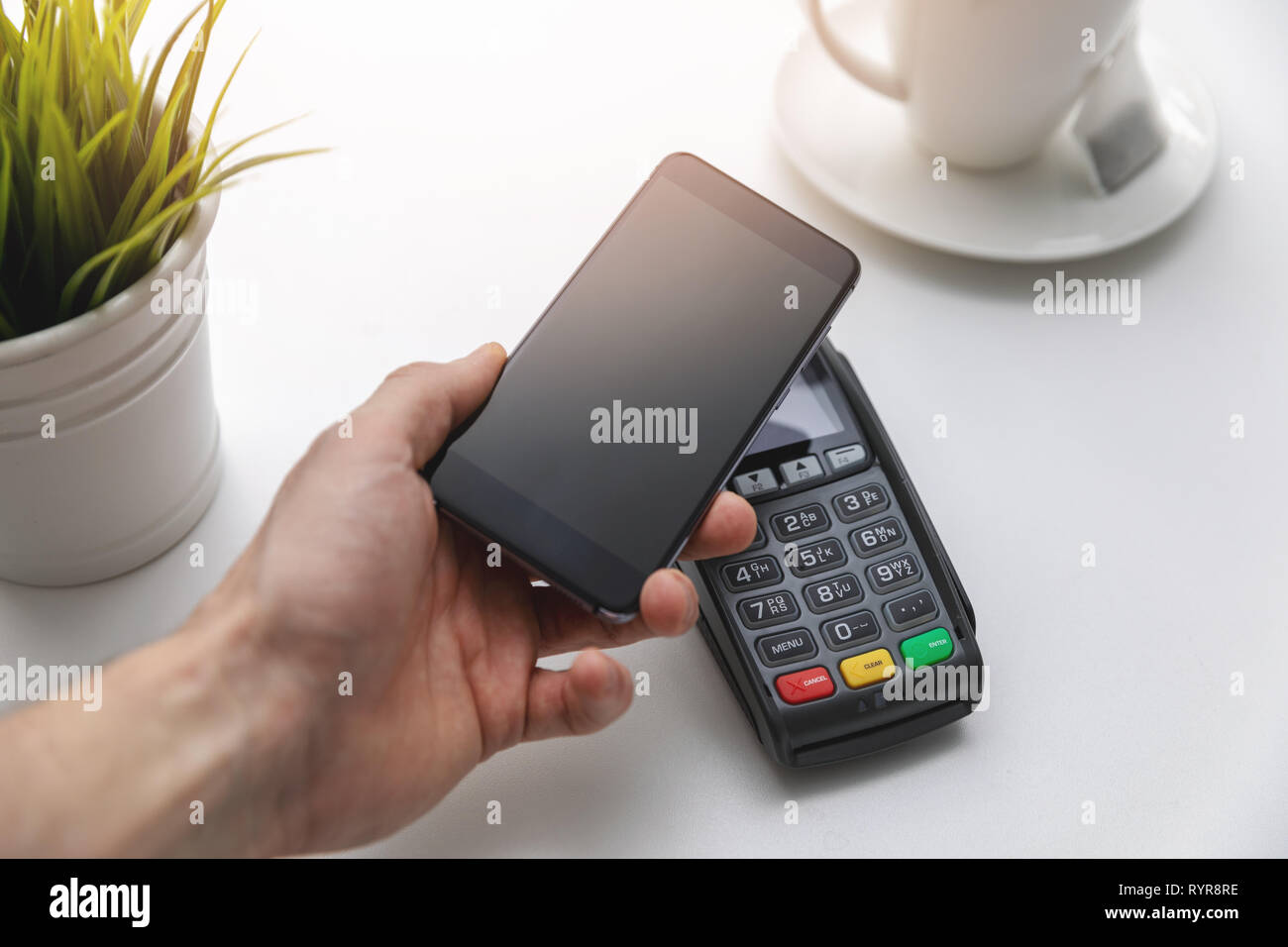 Nfc pagamenti contactless - mano azienda telefono sopra il terminale di pagamento Foto Stock