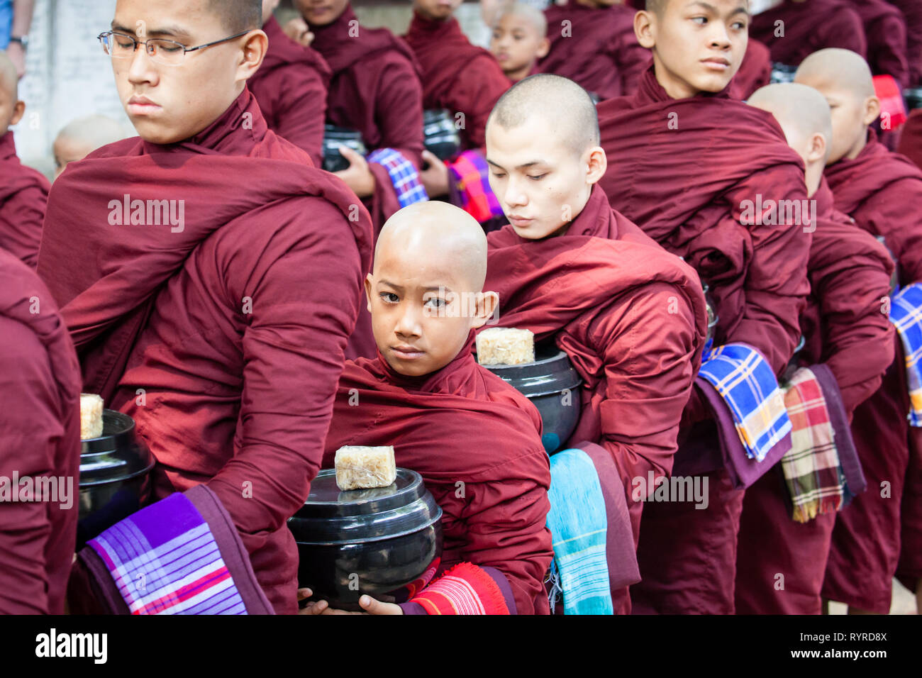 I monaci buddisti coda per il loro pranzo al Monastero Mahagandhayon situato in Amarapura, Myanmar Foto Stock