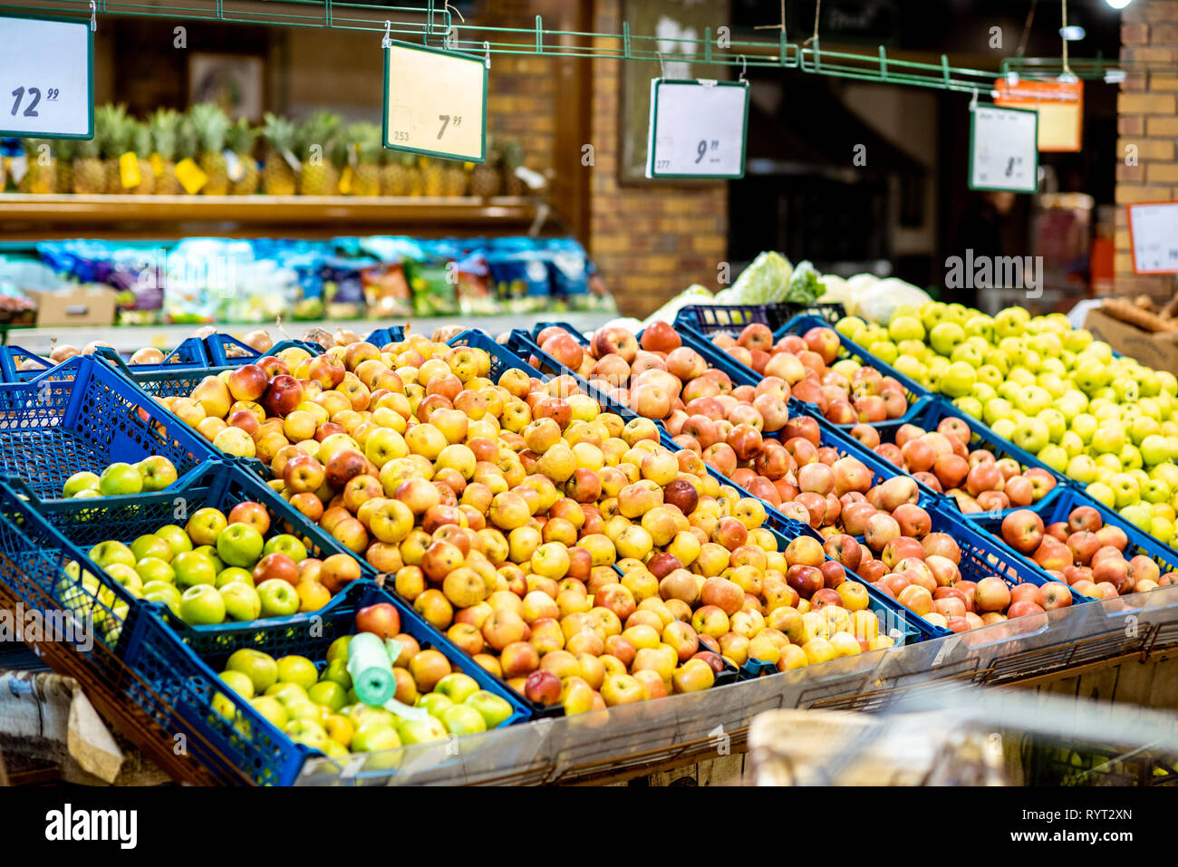Partite di mele nelle caselle in reparto con la frutta fresca e verdura al supermercato Foto Stock