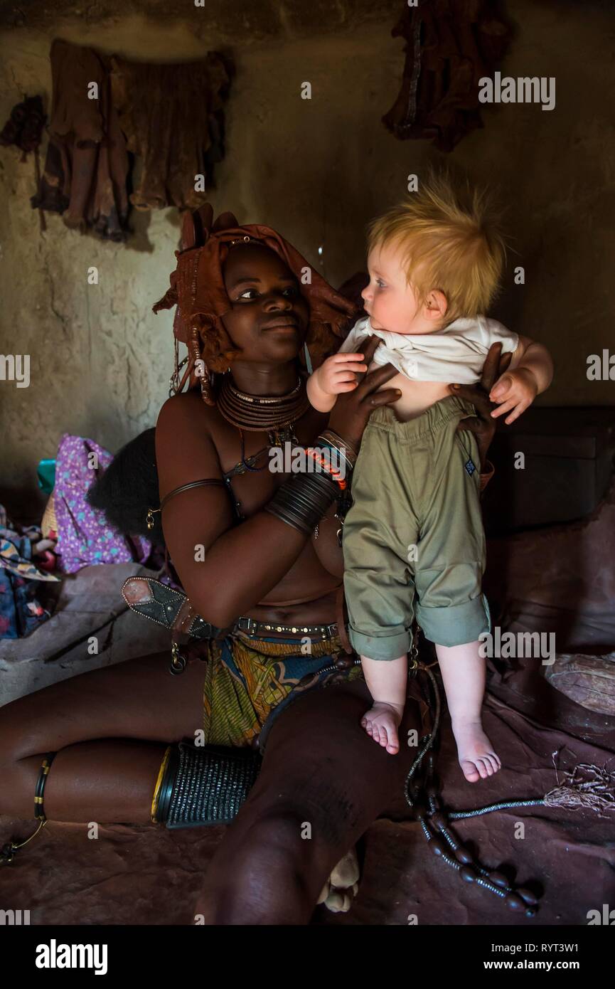 Donna Himba tenendo un turista bianco baby, Kaokoland, Namibia Foto Stock