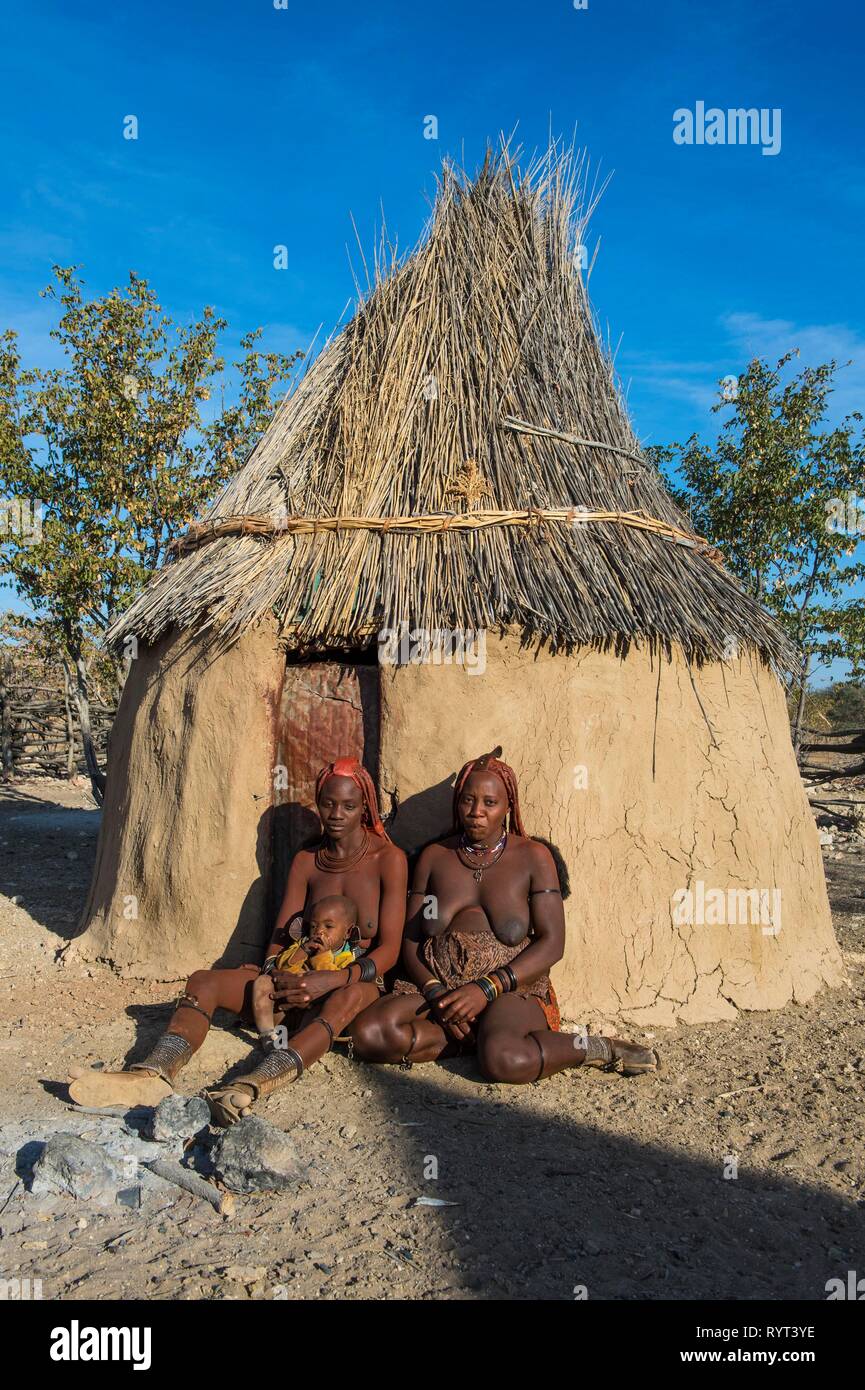 Le donne himba davanti alla loro capanna, Kaokoland, Namibia Foto Stock