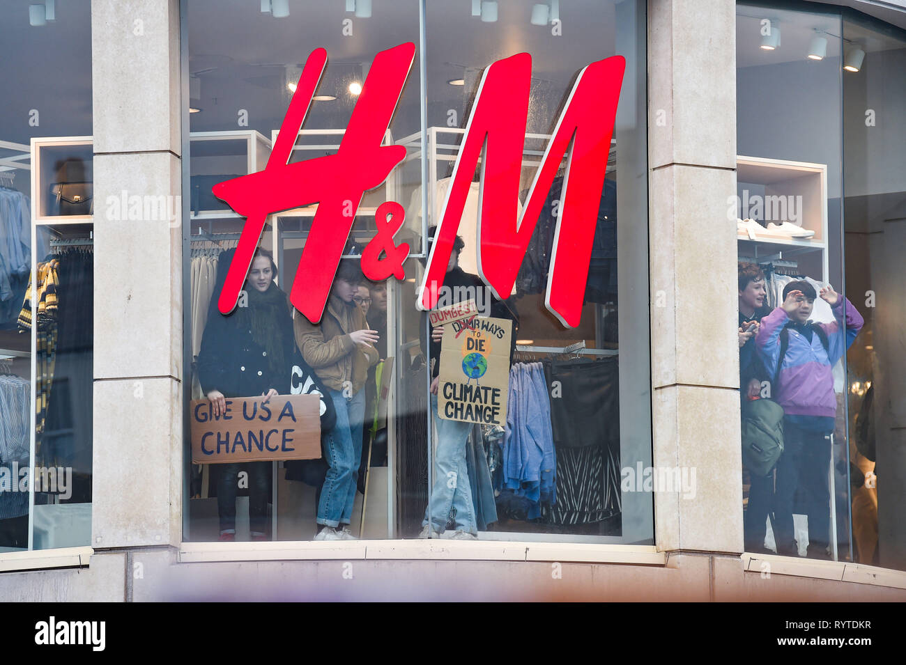 Brighton, Regno Unito. Xv Mar, 2019. I manifestanti di raggiungere l'interno di un H&M negozio di moda come migliaia di studenti gli allievi e i genitori marzo attraverso la Brighton che prendono parte alla seconda giovinezza Strike 4 clima oggi protesta come parte di una coordinata giornata di azione globale. Migliaia di scolari e studenti sono impostati per andare in sciopero a 11am oggi come parte di un global youth action protesta contro il cambiamento climatico Credito: Simon Dack/Alamy Live News Foto Stock