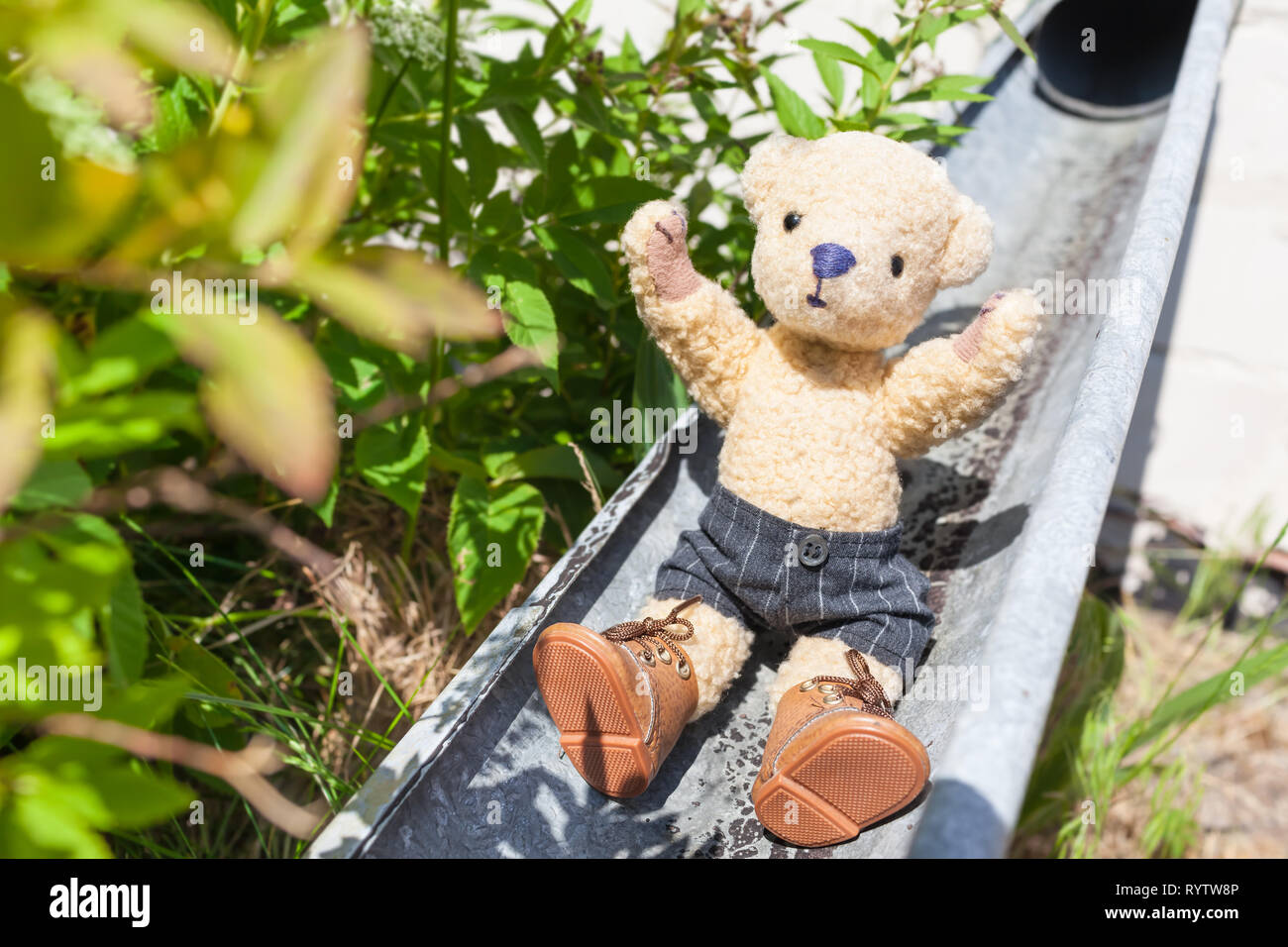 Piccolo monello teddy godersi la vita da far scorrere verso il basso in corrispondenza di aprire canalizzazione delle acque piovane Foto Stock