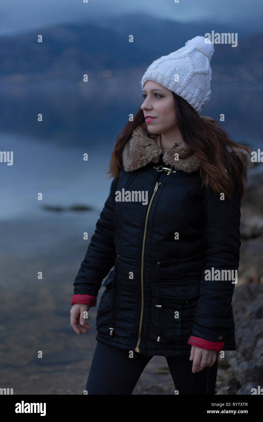 Ragazza giovane di fronte ad un lago durante un giorno nuvoloso Foto Stock