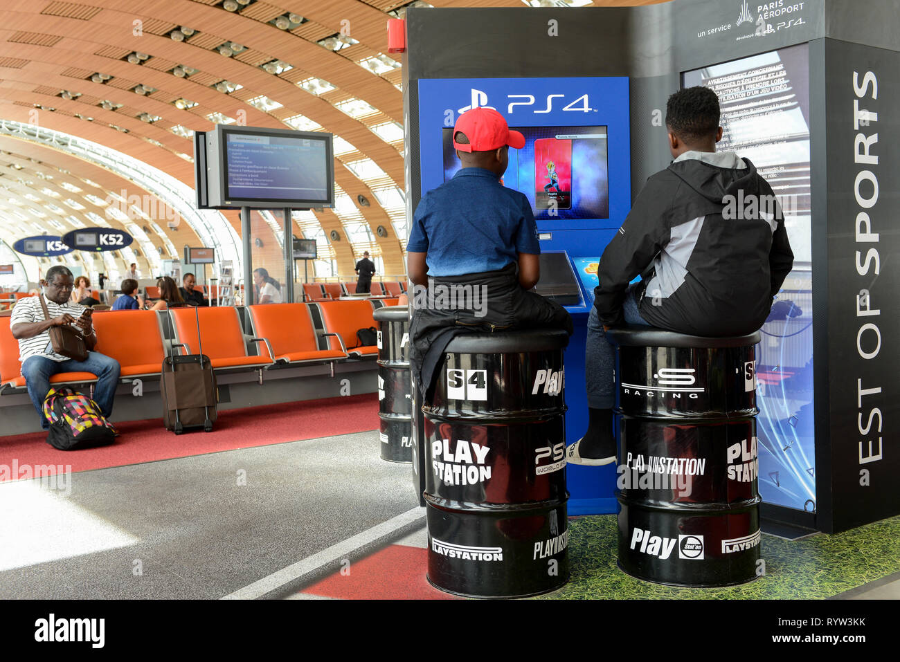 Francia, Parigi Charles de Gaulle, due ragazzi africani seduto sulla canna di stagno e gioco Sony PS4 Playstation in area di attesa alle porte Foto Stock