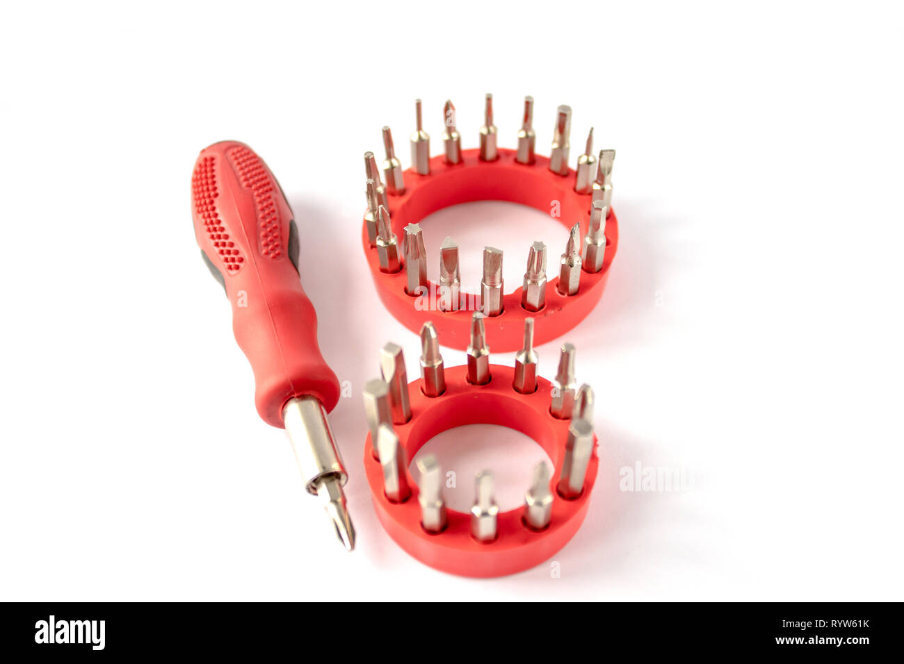 Un cacciavite con manico rosso, set di cacciavite capi (bit) per attrezzi, close-up, il fuoco selettivo su uno sfondo bianco. Foto Stock