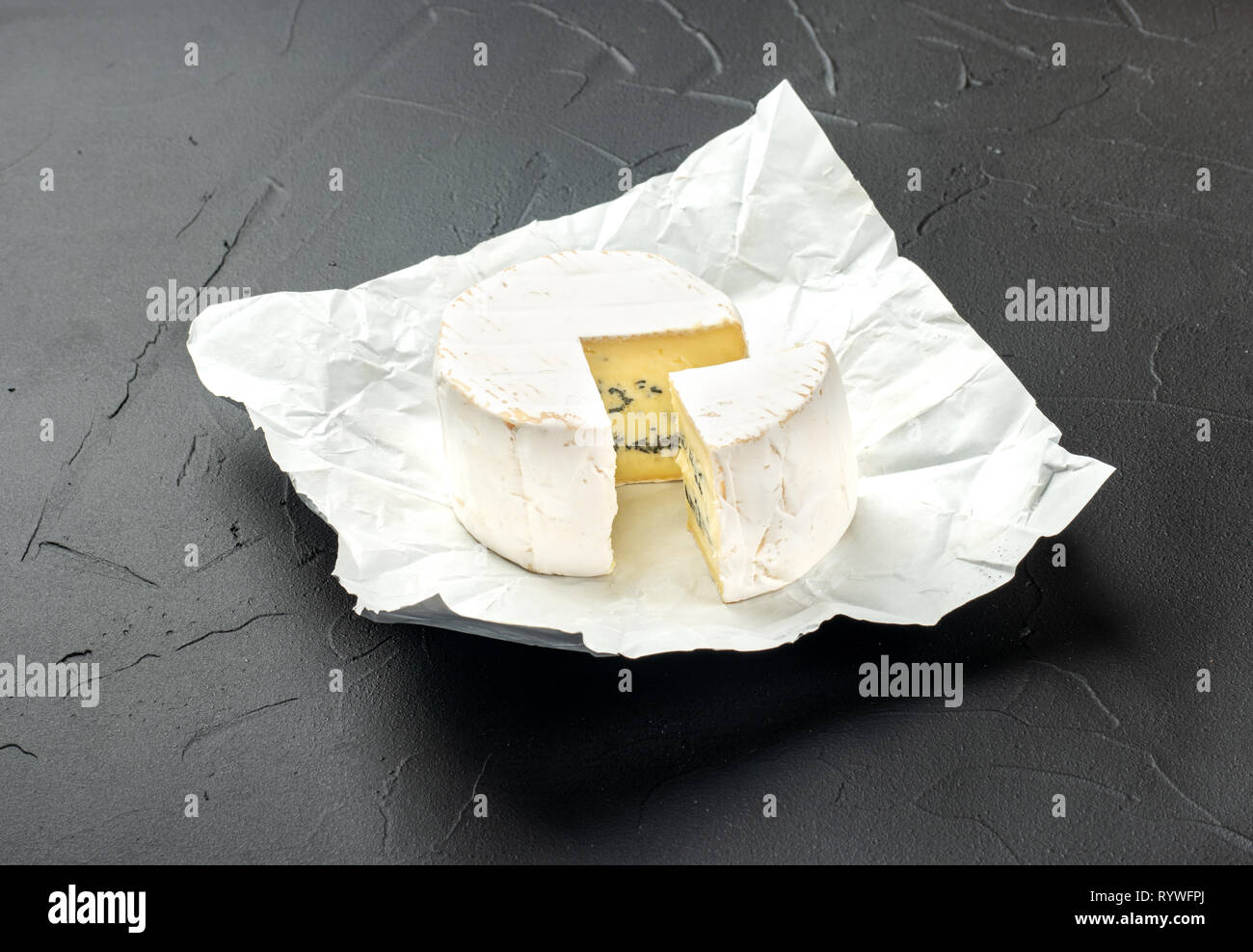 Formaggio Brie con una fetta di carta nella confezione aperta su sfondo scuro Foto Stock