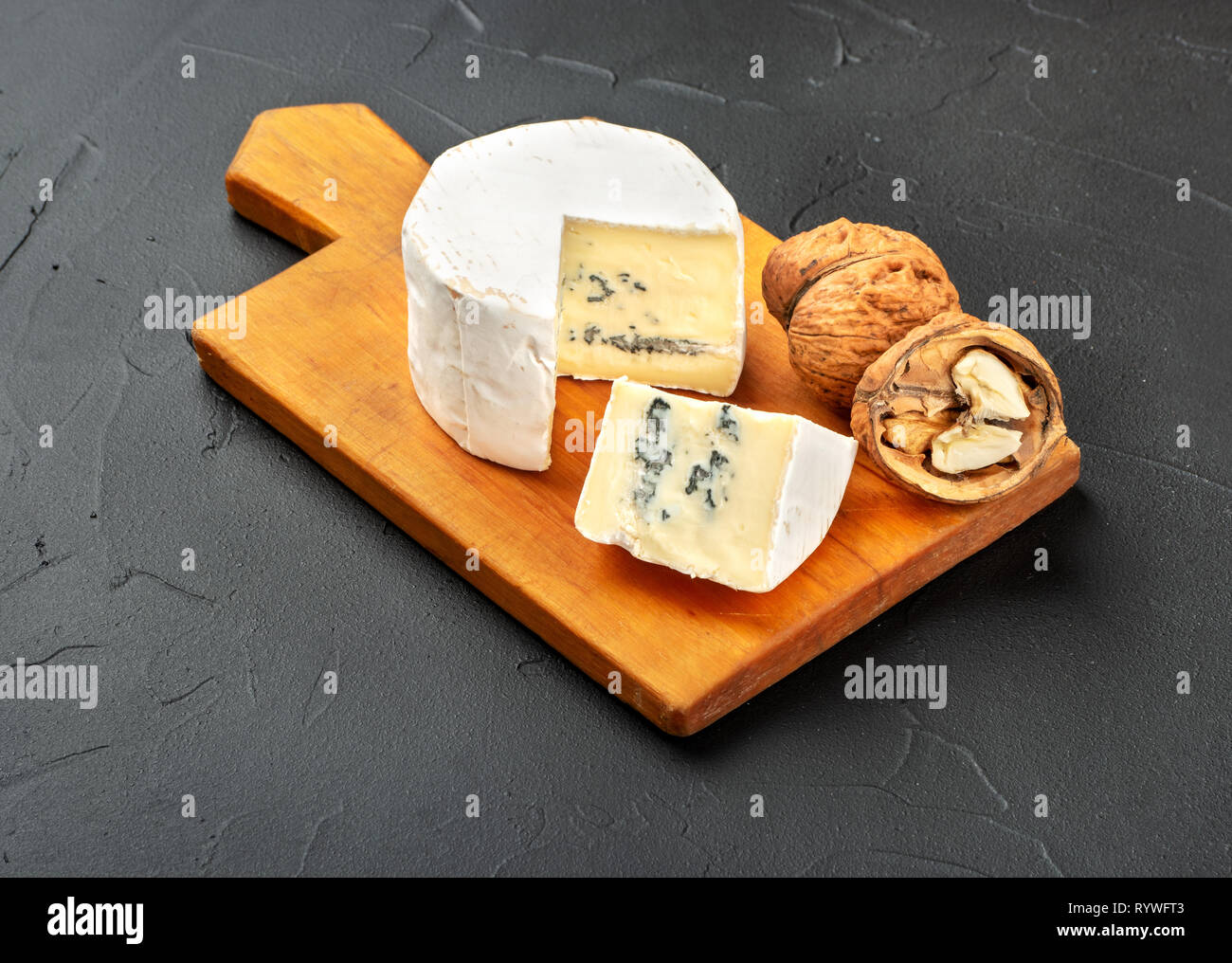 Formaggio Brie con fetta sul tagliere e scuro dello sfondo in calcestruzzo Foto Stock