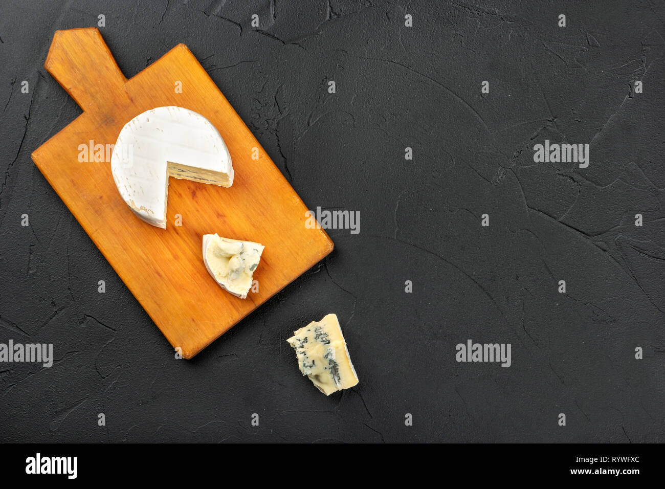 Formaggio Brie con due sezioni sul tagliere in legno scuro di sfondo, vista dall'alto Foto Stock