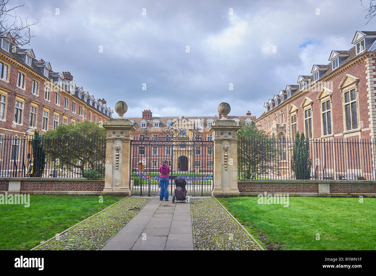 La madre e il bambino stand e lo sguardo al cancello chiuso ingresso al St Catherine's College, Università di Cambridge, Inghilterra. Foto Stock