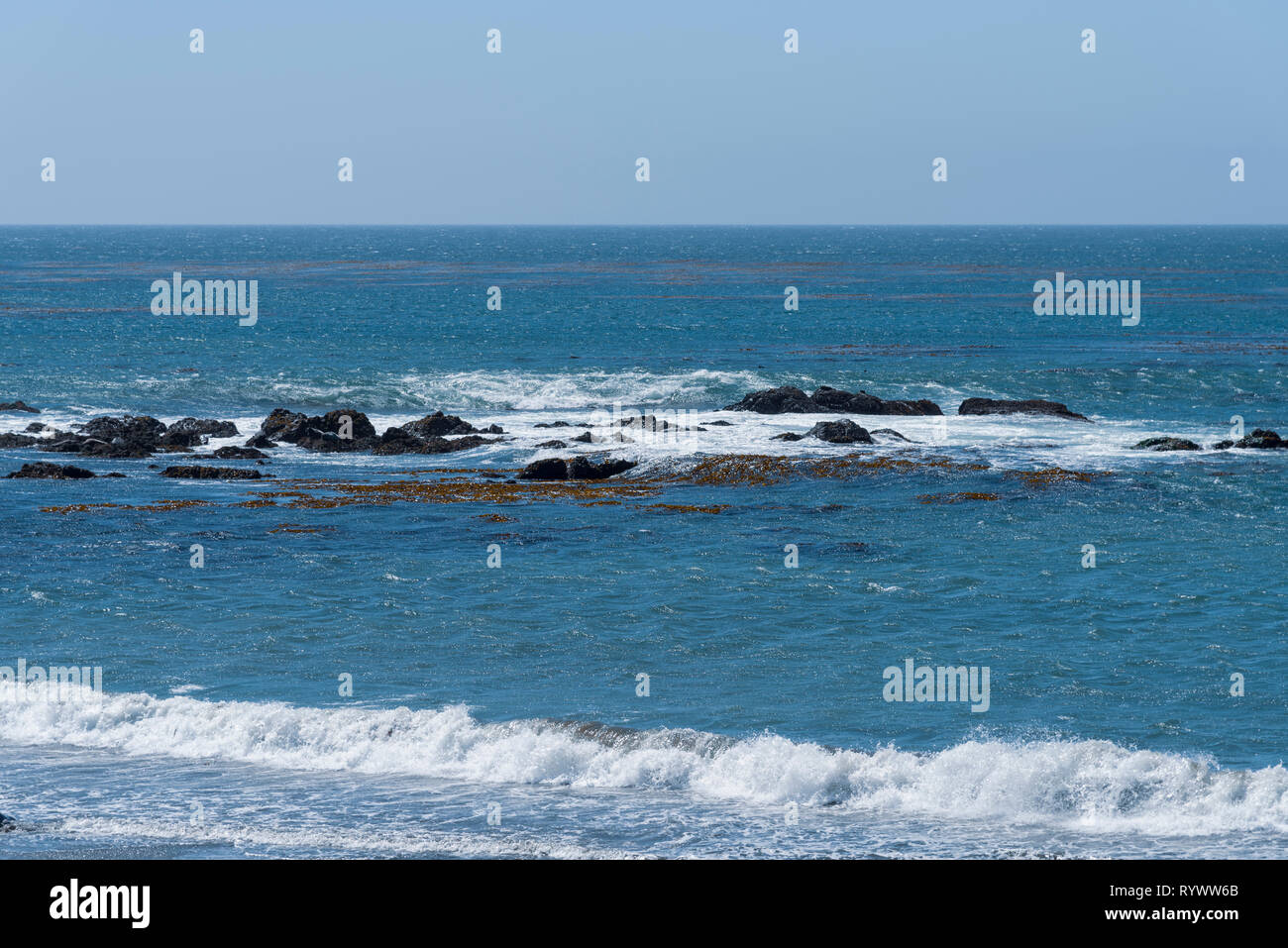 Blu del mare con onde che si infrangono contro le rocce. Foto Stock