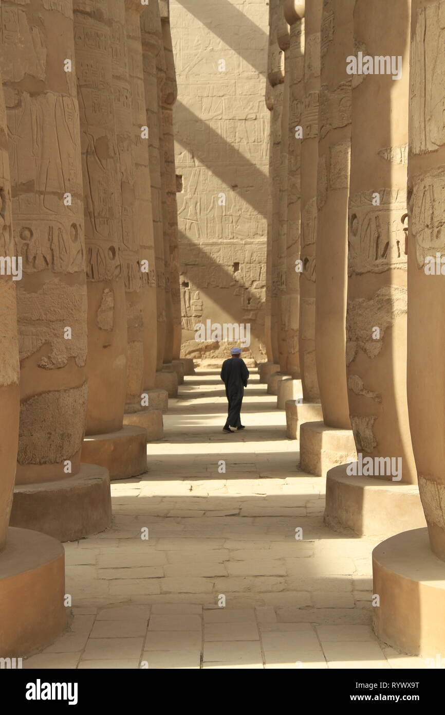 Protezione del tempio a piedi attraverso le colonne del grande Hypostyle Hall, Tempio di Karnak complessa, nei pressi di Luxor, l'Alto Egitto Foto Stock