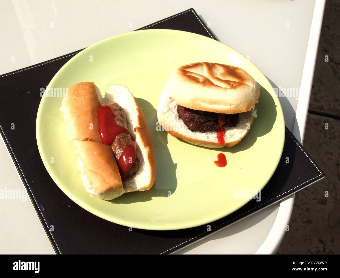 Insaccato in un panino con ketchup e hamburger in un panino con ketchup sulla piastra. Foto Stock