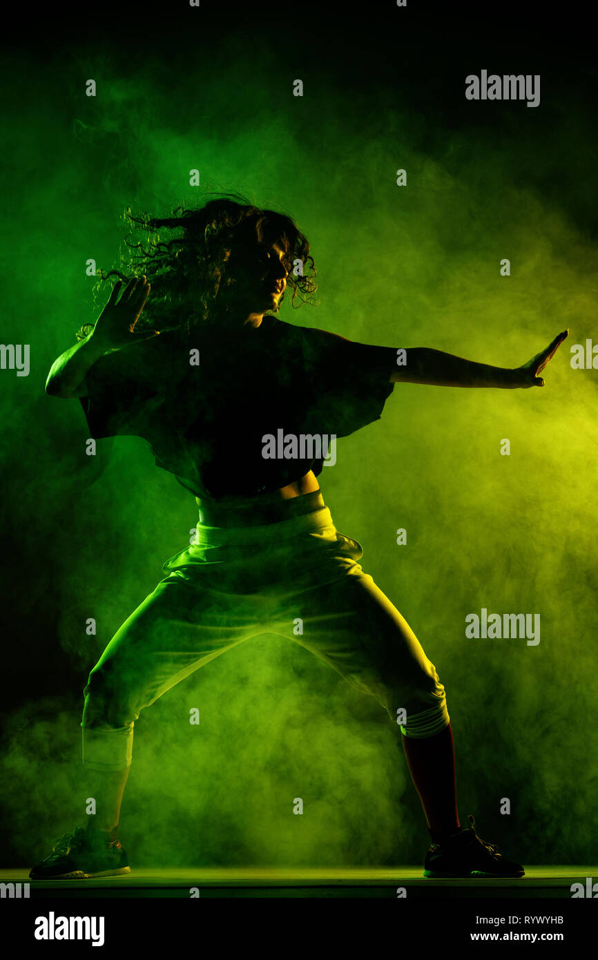 Silhouette di una ragazza ballare zumba, fumo in background Foto Stock