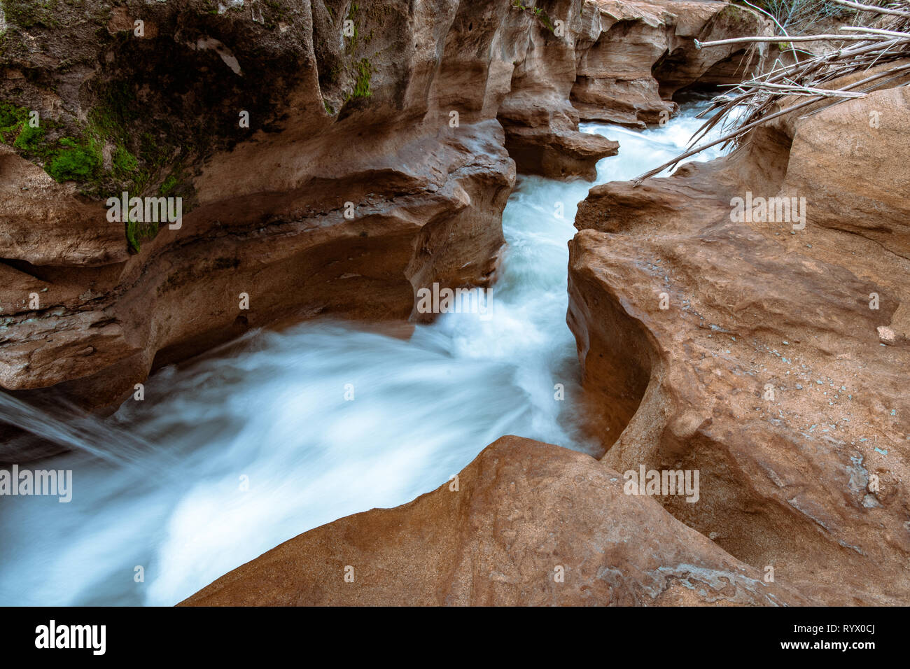 L'acqua che scorre e cascata attraverso una pietra arenaria slot canyon. Silky effetto dell'acqua con un flusso di acqua blu. Foto Stock