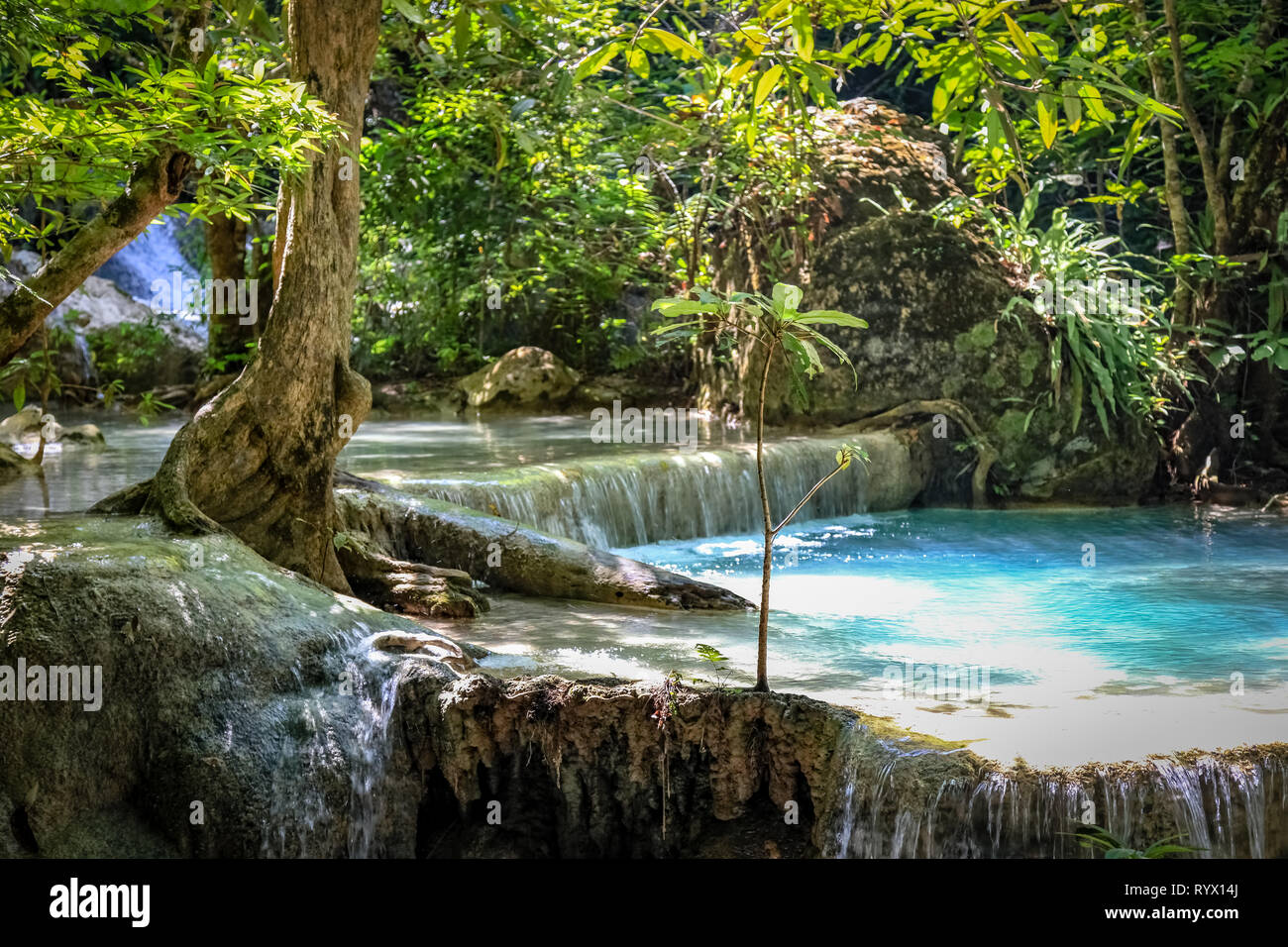 Primo piano di un chiaro blu piscina di acqua e una breve cascata nel Parco Nazionale di Erawan Foto Stock