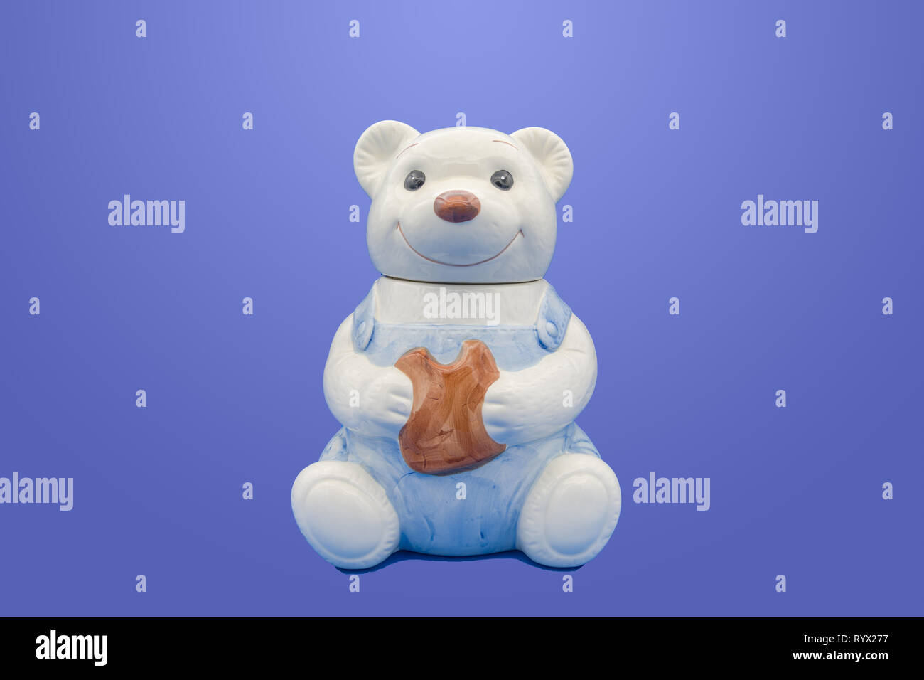 Una ceramica smaltata vaso di biscotti a forma di orsacchiotto isolato su sfondo blu Foto Stock