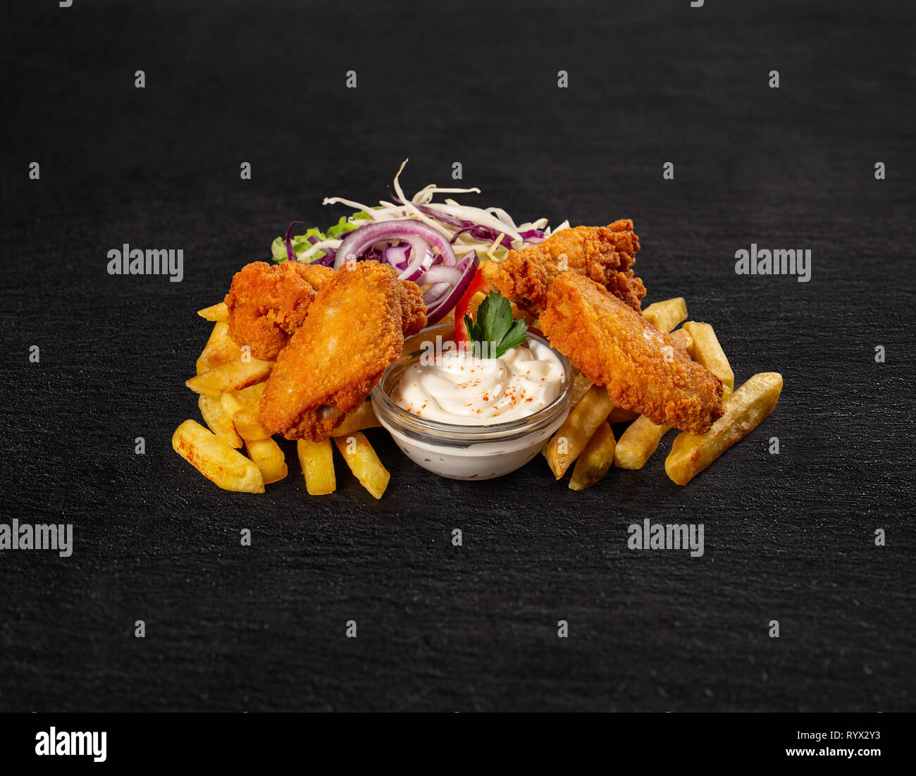 Le ali di pollo croccanti con patatine fritte sul nero ardesia sfondo Foto Stock