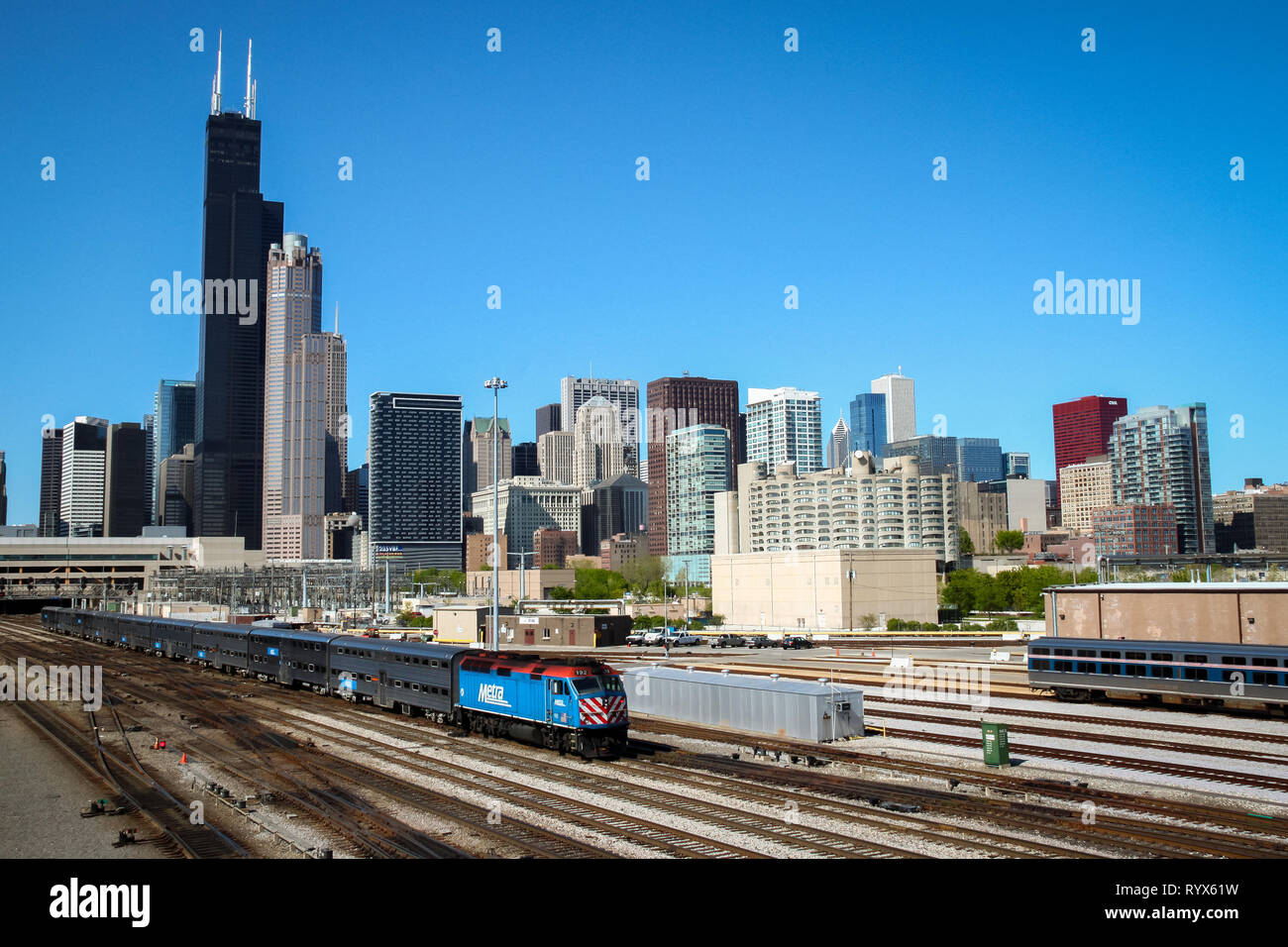 Un treno che passa nella parte anteriore del Chicago skyline della città in una luminosa giornata di sole con cielo blu Foto Stock