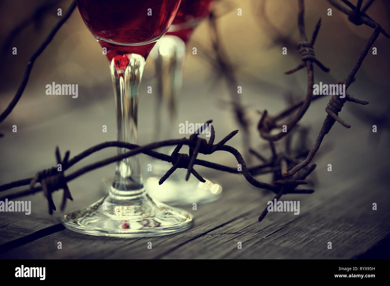 Rusty il filo spinato e bicchieri di vino rosso su una tabella. Dipendenza alcolica. Foto Stock