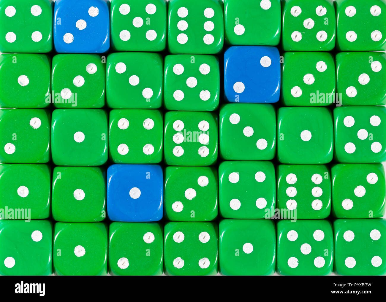 Sullo sfondo di un casuale verde ordinato plinti con tre cubi blu Foto Stock