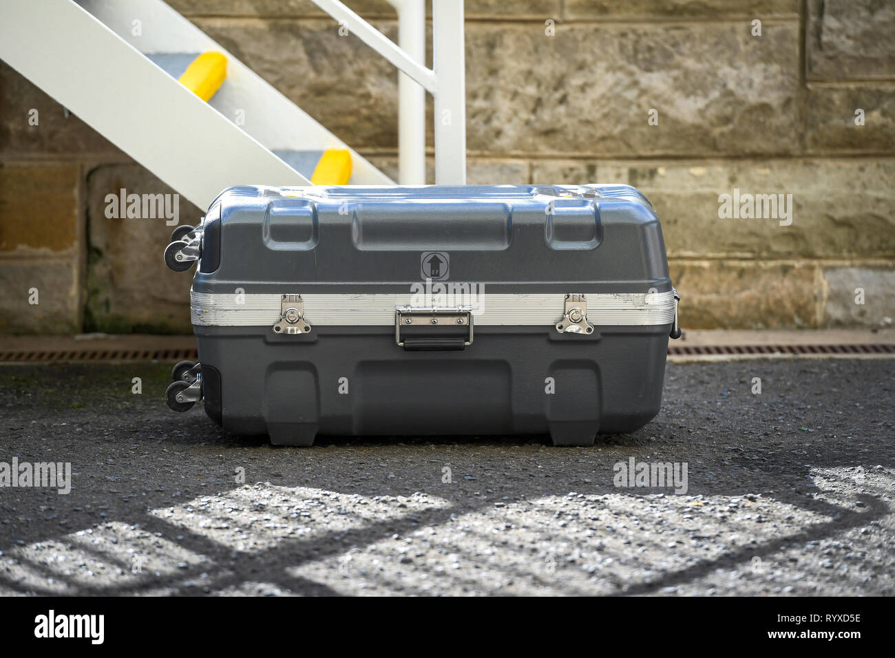 Immagine di un astuccio rigido valigia posa sul percorso di calcestruzzo Foto Stock