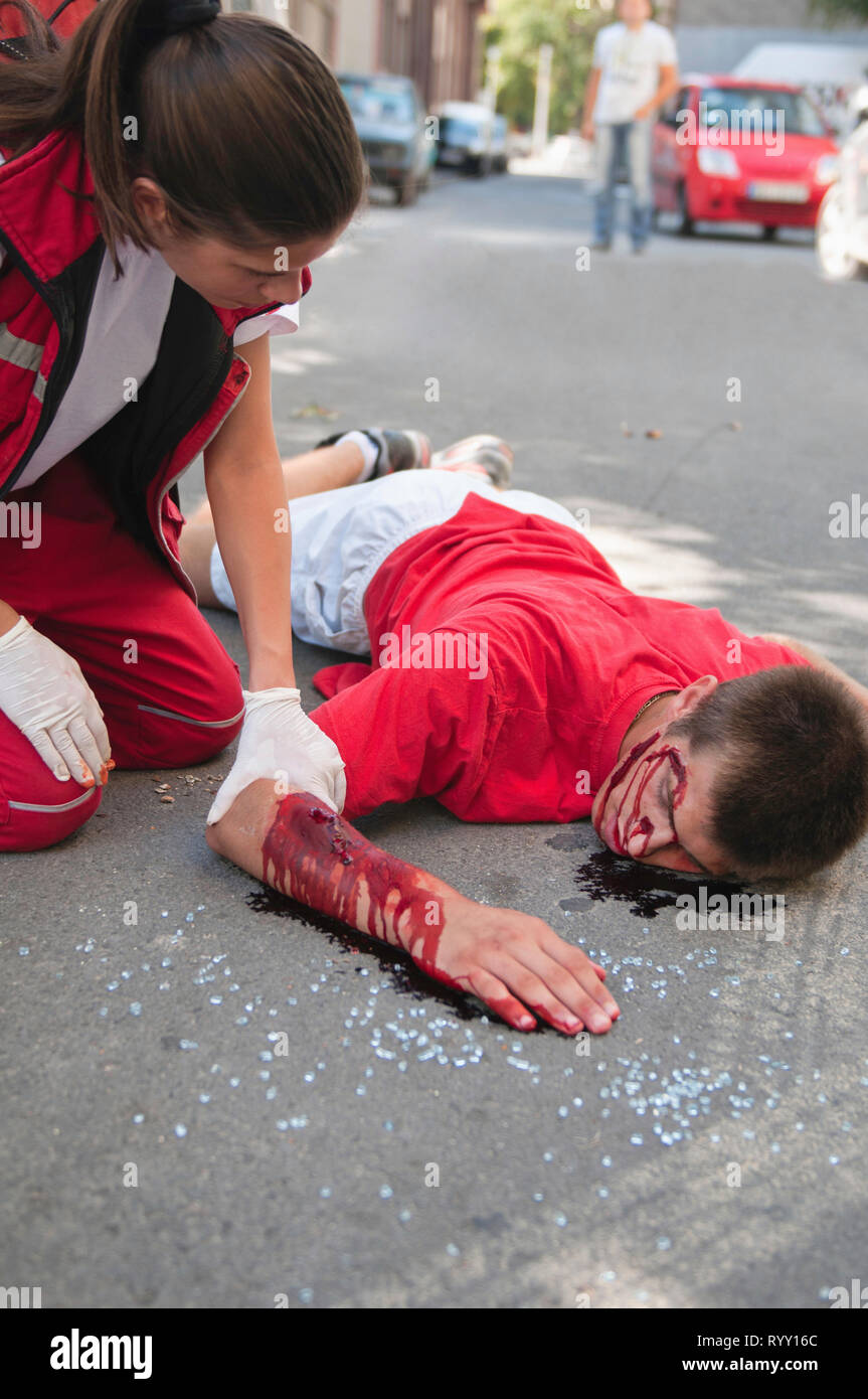 Paramedico con auto vittima di incidenti sulla strada. Esercitazione simulata con medico sotto la supervisione medica realistica per il make-up. Foto Stock