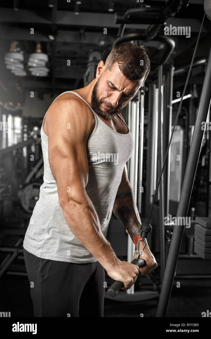 Bodybuilding. Uomo Barbuto doingcable permanente braccio rettilineo pulldown in palestra concentrate Foto Stock