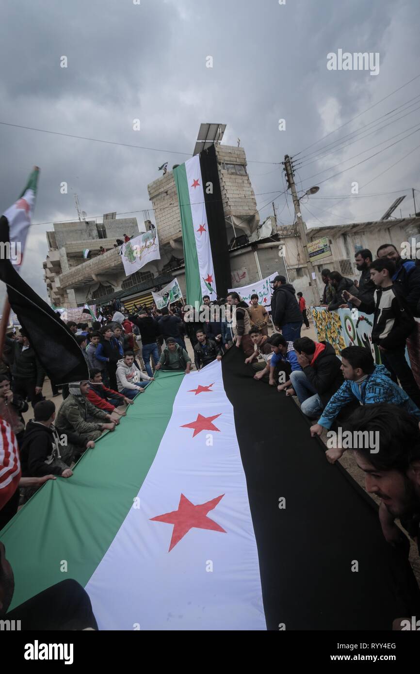 Siri sono visti trattenere un flag di opposizione durante la celebrazione. Siri nella città di Bensh, che si trova a est di Idlib e controllati dall'opposizione, celebrato l'ottavo anniversario della rivolta contro il regime del Presidente Bashar al-Assad. Foto Stock